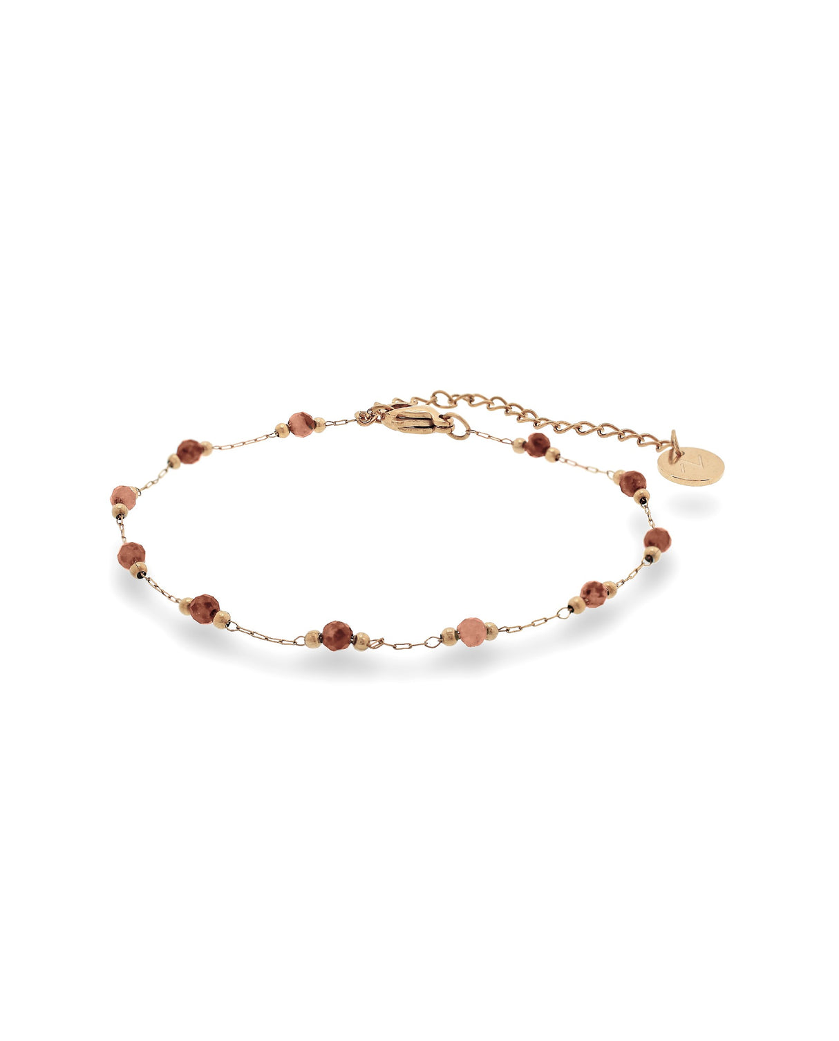 Pulsera fina dorada con piedras rojas.
