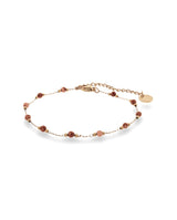 Pulsera fina dorada con piedras rojas.