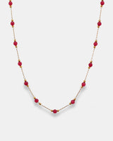 Collar en acero dorado con pequeñas cuentas rojas.