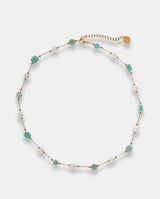 Collar en acero dorado con piedras verdes irregulares y pequeñas piedras blancas.