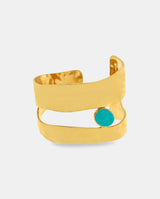 Brazalete ancho dorado con lineas abiertas y piedra verde.